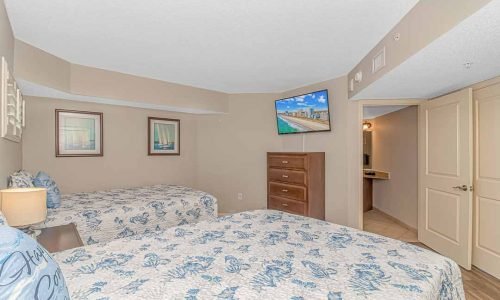 second bedroom with two queen beds, flatscreen TV, storage and bathroom in our Penthouse Condo at Dunes Village